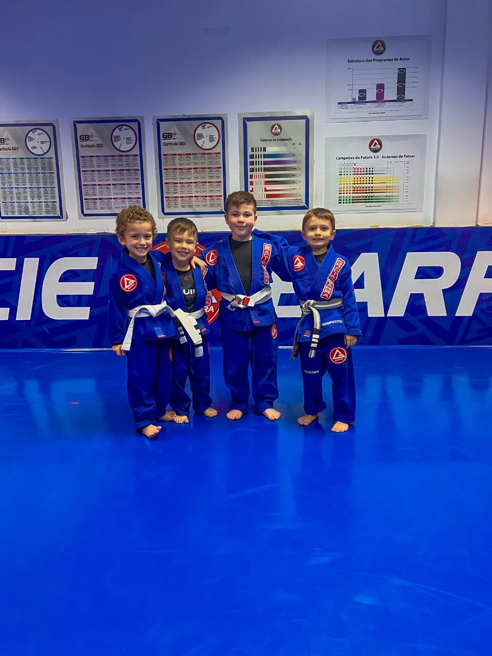Quatro crianças de kimono azul juntas no tatame