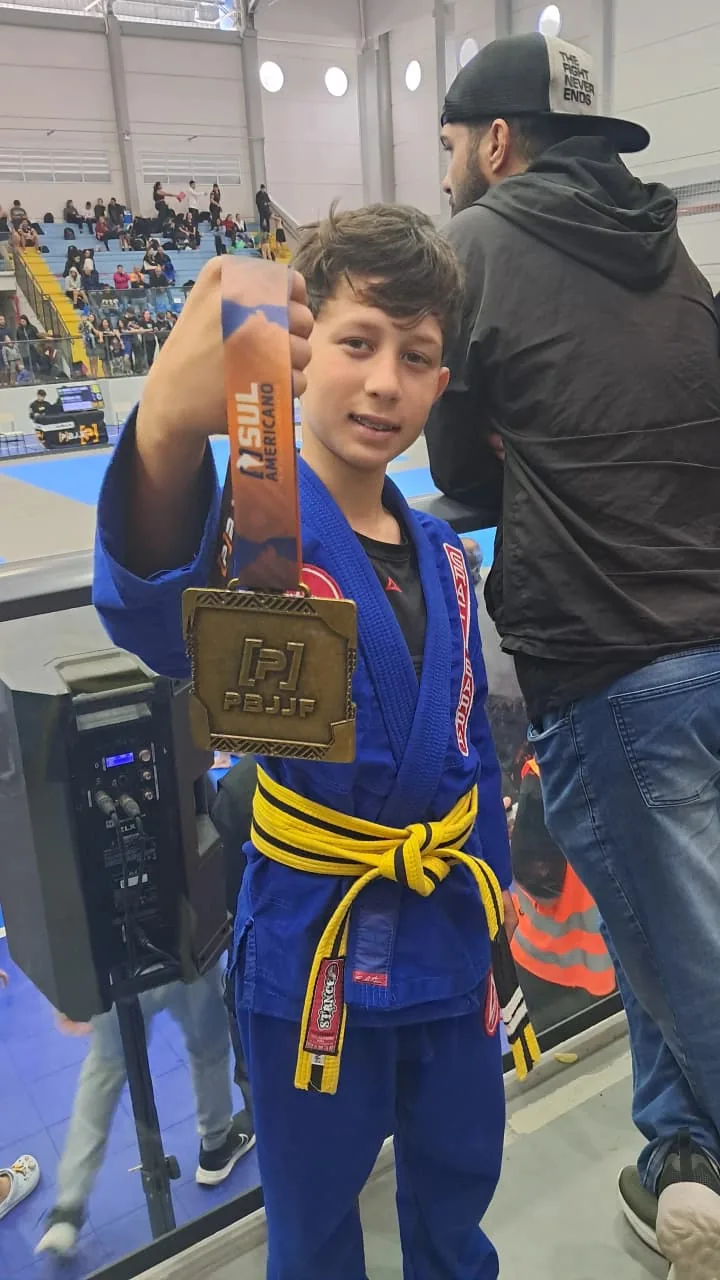 Jovem praticante de faixa amarela com sua medalha